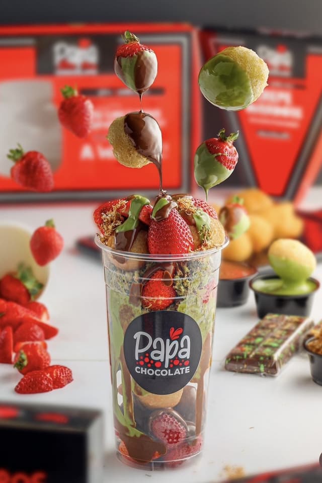 A Papa Chocolate strawberry cup with chocolate and cream